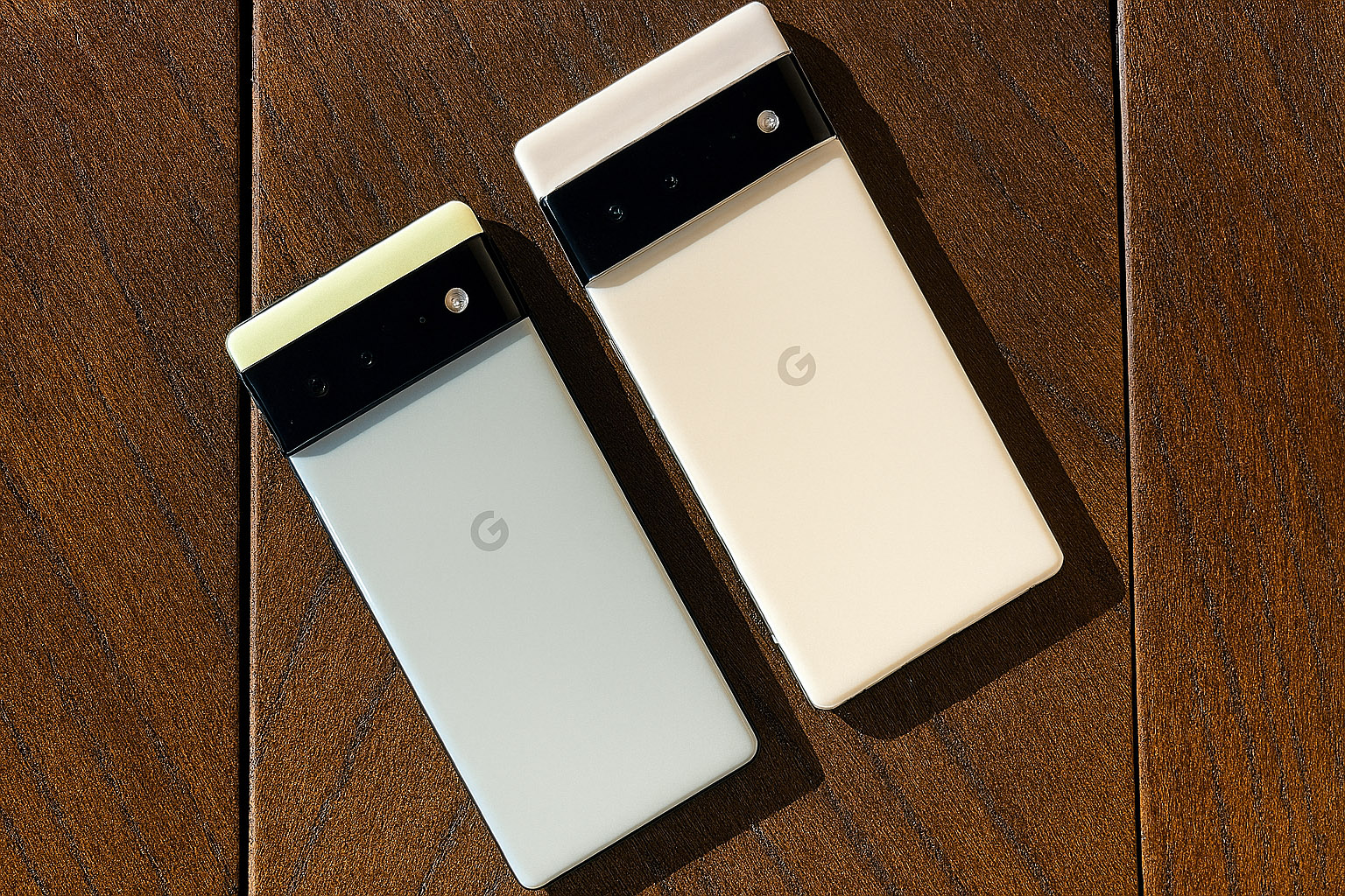 Dva Android telefona na temno rjavi hrastovi mizi, prikaz pregrevanja android naprav v vročem okolju.